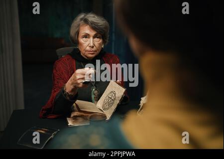 Reife Hexenzauber für Klienten mit Hexenbuch und magischem Pendel Stockfoto