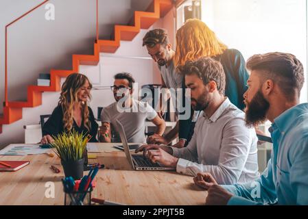 Geschäftsleute im Büro arbeiten während einer Besprechung mit einem Laptop zusammen Stockfoto