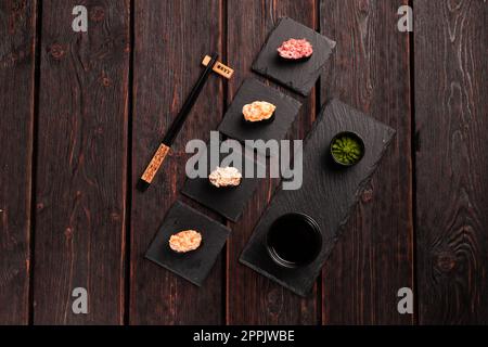 Set aus Gunkan Maki Sushi mit verschiedenen Arten von Fischlachs, Jakobsmuscheln, Barsch, Aal, Garnelen und Kaviar auf Holztisch-Hintergrund. Sushi-Menü. Japanische Speisen Sushi Set Gunkans Blick von oben Stockfoto