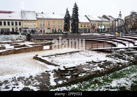 Sremska Mitrovica Serbien 01.27.2023 Schneefall in der Stadt. Historischer Platz von Zitni trg. Alte mehrfarbige Gebäude und Ausgrabungen aus römischer Zeit. Wettervorhersage. Tag Winter. Kulturelles Erbe. Stockfoto