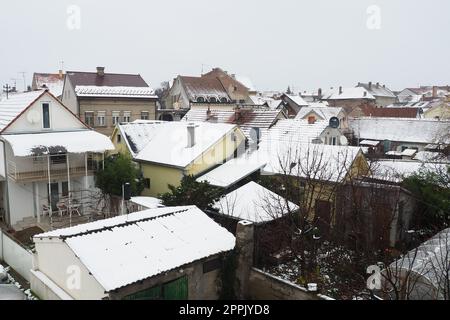 Sremska Mitrovica, Serbien, 01.27.2023 Schneefall in der Stadt. Schneebedeckte Dächer von Häusern. Wettervorhersage. Bewölkter Wintertag. Stadtlandschaft. Herdheizung mit Kohle und Holz. Wirtschaftskrise. Stockfoto