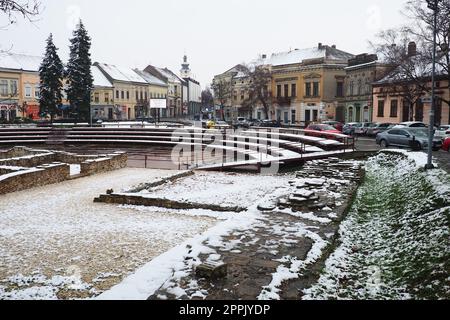 Sremska Mitrovica Serbien 01.27.2023 Schneefall in der Stadt. Historischer Platz von Zitni trg. Alte mehrfarbige Gebäude und Ausgrabungen aus römischer Zeit. Wettervorhersage. Tag Winter. Kulturelles Erbe. Stockfoto