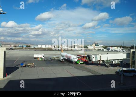 Ankara, Türkei, Flughafen Esenboga Havalimani, 01.19.2023. Sicht vom Fenster des Passagierterminals auf die Landebahn. Flugzeugbrücke. Passagiere mit Koffern steigen aus dem Flugzeug aus. Himmel Stockfoto