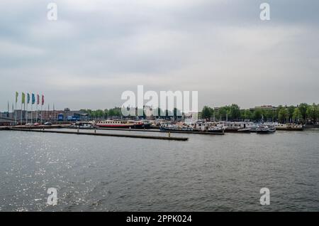 AMSTERDAM, NIEDERLANDE - 24. AUGUST 2013: Blick auf Amsterdam mit Fluss und Booten, in der Nähe des Hauptbahnhofs Stockfoto