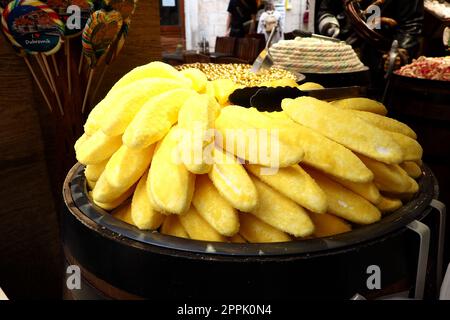 Eclairs in Form von gelben Bananen auf einem Gericht. Ein Schaukasten des Süßigkeitenladens Dubrovnik Croatia. Leckere süße Kuchen werden Touristen zum Verkauf angeboten. Ungewöhnliche Form des Backens mit pulvergelbem Zucker. Stockfoto