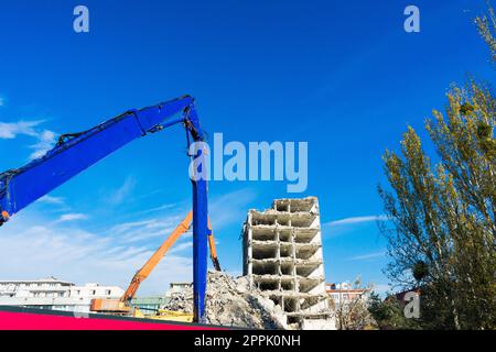 Abriss des alten Gebäudes mit Sloopkraan gegen den blauen Wolkenhimmel. Stockfoto