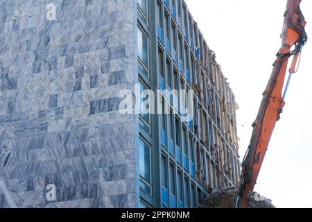 Abriss des alten Gebäudes mit Sloopkraan gegen den blauen Wolkenhimmel. Stockfoto