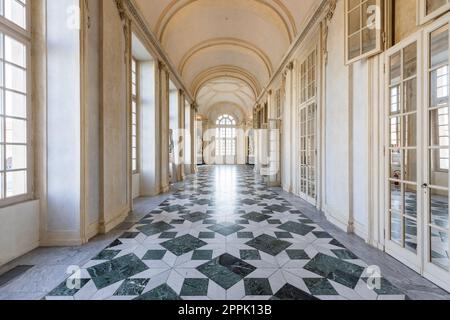 Venaria reale, Italien - Januar 2023: Luxuriöser Innenraum des alten Königspalastes. Galerieperspektive mit Fenster. Stockfoto