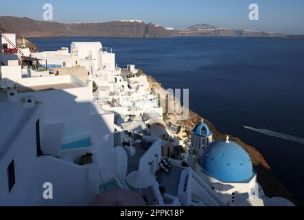 Blick vom Aussichtspunkt auf das Dorf Oia mit der blauen Kuppel der griechisch-orthodoxen christlichen Kirche und der traditionellen, weiß getünchten griechischen Architektur. Santorini, Griechenland Stockfoto