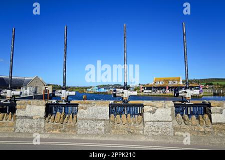 Blick über den River Bit in Richtung des Rise Riverside Restaurants mit Sluice Gate Motorpfosten im Vordergrund, West Bay, Dorset, Großbritannien. Stockfoto