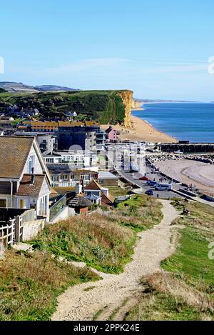 Erhöhte Aussicht über die Dächer der Stadt in Richtung Strand, Klippen und Landschaft vom South West Coast Path, West Bay, Dorset, Großbritannien. Stockfoto