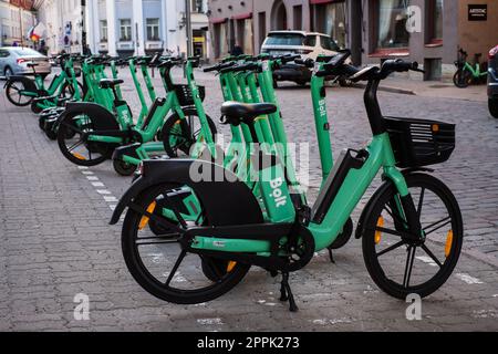 Tallinn, Estland - 21. April 2023: Bolt-Elektroroller. Geparkte grüne elektrische Leihfahrräder in einer Straße der Stadt. Stockfoto