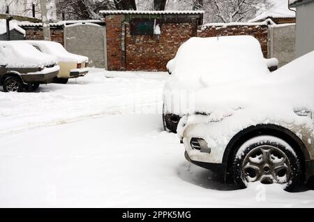 Fragment des Autos unter der Schneeschicht nach dem starken Schneefall. Die Karosserie des Autos ist mit weißem Schnee bedeckt Stockfoto