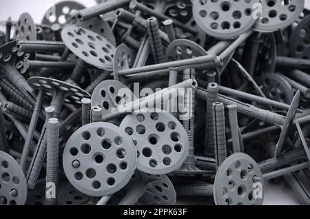 Hintergrund Muster von vielen grauen Kunststoff Dübel (Befestigung) für die Wärmedämmung. Ein riesiger Stapel von Armaturen für die Installation von geschäumten Polystyrolplatten für die Dämmung der Gebäudewände Stockfoto