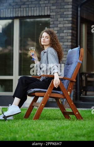 Schöne Frau sitzt auf einem Stuhl im Garten Stockfoto