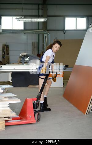 Frau zieht Hydraulikwagen in Zimmermannswerkstatt Stockfoto