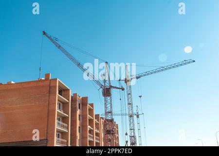 Baustelle mit Kran. Langfristiger Bau. Ein neues Gebäude im Bau, von unten nach oben. Unfertiger Wolkenkratzer, gefrorener Bau. Unfertiger Bau einer mehrstöckigen Wohngegend Stockfoto