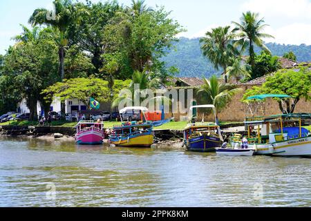 PARATY, BRASILIEN - 25. DEZEMBER 2022: Uferpromenade mit traditionellen bunten Booten des historischen Zentrums von Paraty, Rio de Janeiro, Brasilien Stockfoto