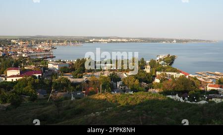 Kerch 21. August 2021 Blick auf die Stadt Kerch von der Aussichtsplattform auf dem Berg Mithridat. Häuser, Bäume, Schwarzes und Asowisches Meer, Seehafen. Cove und gegenüber der Küste mit Horizont. Sommerabend Stockfoto