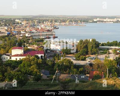 Kerch 21. August 2021 Blick auf die Stadt Kerch von der Aussichtsplattform auf dem Berg Mithridat. Häuser, Bäume, Schwarzes und Asowisches Meer, Seehafen. Cove und gegenüber der Küste mit Horizont. Sommerabend Stockfoto