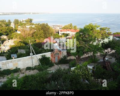 Kerch 21. August 2021 Blick auf die Stadt Kerch von der Aussichtsplattform auf dem Berg Mithridat. Häuser, Bäume, Schwarzes und Asowisches Meer, Seehafen. Cove und gegenüber der Küste mit Horizont. Sommerabend Stockfoto