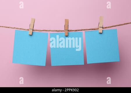 Holzkleidekabinen mit unbeschrifteten Notizzetteln auf pinkfarbenem Hintergrund. Platz für Text Stockfoto