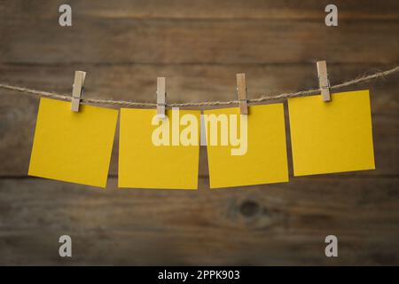 Kleiderschränke mit leeren Notizzetteln auf Garn vor Holzhintergrund. Platz für Text Stockfoto