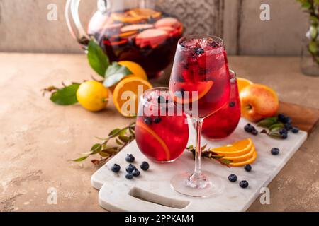 Erfrischende Sommerbeeren-Sangria mit Äpfeln, Orangen und Blaubeeren in Weingläsern mit Eis Stockfoto