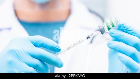 Arzt man Spritze auf Flüssigflasche COVID-19 (Coronavirus) Impfstoff zur Injektion im Krankenhaus ziehen Stockfoto