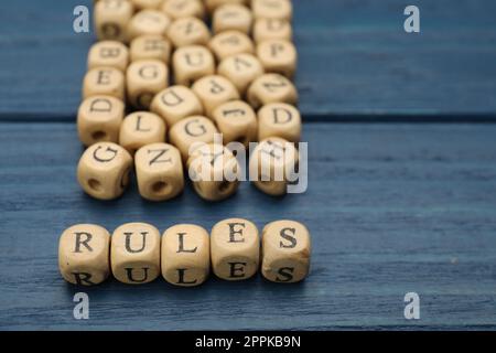 Wortregeln aus Würfeln mit Buchstaben auf einem blauen Holztisch Stockfoto