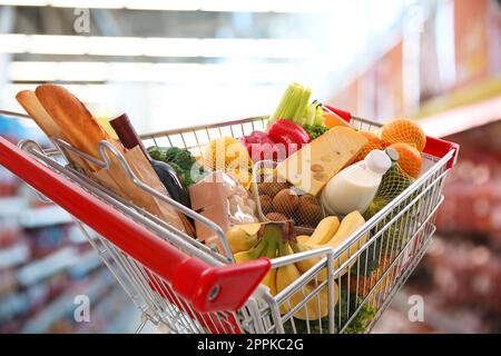 Einkaufswagen mit verschiedenen Lebensmitteln im Supermarkt Stockfoto