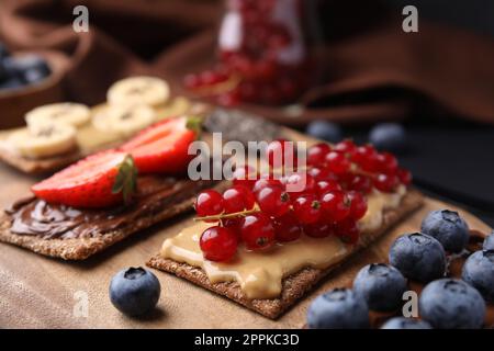 Frisches knuspriges Roggen-Knusperbrot mit verschiedenen Belägen auf Holzbrett, Nahaufnahme Stockfoto