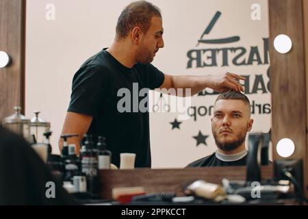 Der Friseur frisiert im Friseursalon mit einer Schere Stockfoto