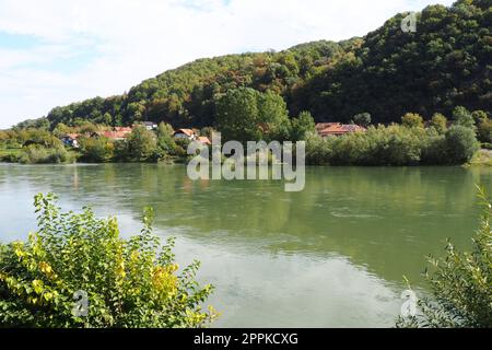 Mali Zvornik, Serbien, 29. September 2022. Fluss Drina in der Nähe von Banja Koviljaca, Blick auf die Küste Serbiens von BiH. Der Fluss des Wassers, grün am gegenüberliegenden Ufer des Flusses. Wohnhäuser. Stockfoto