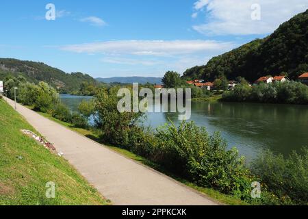 Mali Zvornik, Serbien, 29. September 2022. Fluss Drina in der Nähe von Banja Koviljaca, Blick auf die Küste Serbiens von BiH. Der Fluss des Wassers, grün am gegenüberliegenden Ufer des Flusses. Wohnhäuser. Stockfoto