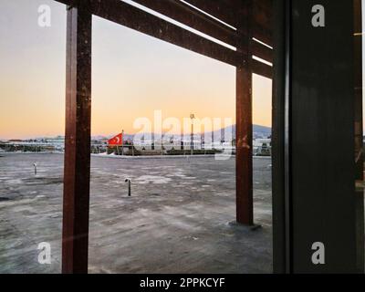 Istanbul Türkei, Flughafen Sabiha Gokcen Uluslararasi Havalimani 04.08.2022 Blick aus dem Fenster auf Istanbul durch das Glas. Türkische Flagge, Hydranten oder Ventilation. Sonnenuntergang über den Bergen. Stockfoto