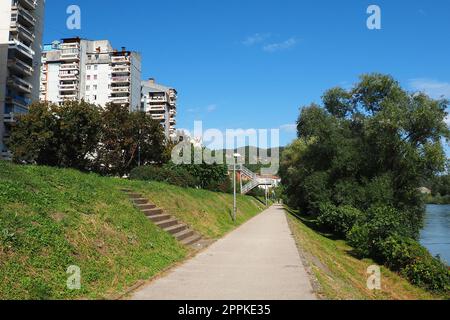 Zvornik, Bosnien und Herzegowina, 1. Oktober 2022, Fußgängerböschung entlang der Drina, Grenze zu Serbien. Wohngebäude, Waldparkgebiet. Mount Velavnike. Sonniger Sommertag. Stockfoto