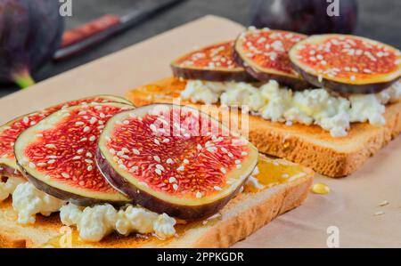 Toast mit Feigen, Honig und Ricotta, Nahaufnahme. Gezielter Fokus auf Bruchetta, Frühstücksidee oder Foto für Menü, mediterranes Frühstück Stockfoto