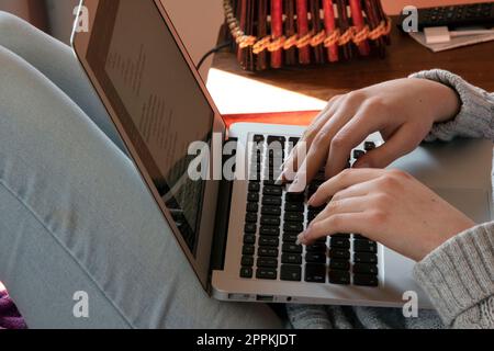 Frau, die mit Computer von zu Hause aus auf dem Sofa arbeitet Stockfoto