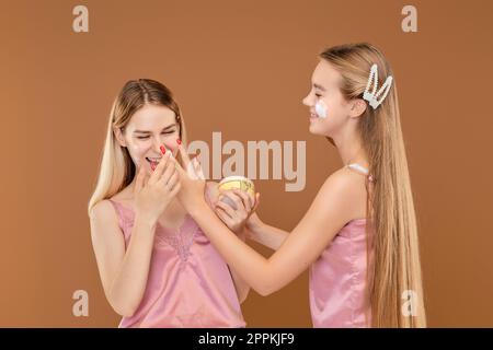 Zwei junge Mädchen, die ihr Gesicht mit Akne-Creme auftragen Stockfoto