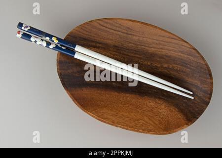 Minimalistische Szene mit leerer Holzschüssel und Essstäbchen, Draufsicht Stockfoto