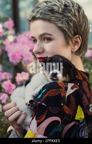 Nahaufnahme einer blonden Frau, die das Hündchen im Gartenporträt hält Stockfoto