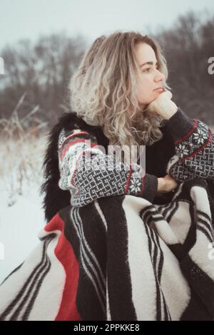 Nahaufnahme einer hübschen Frau mit warmer Decke im verschneiten Feldporträt Stockfoto