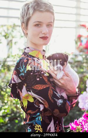 Nahaufnahme einer hübschen Dame mit niedlichem Welpen im Gartenporträt Stockfoto
