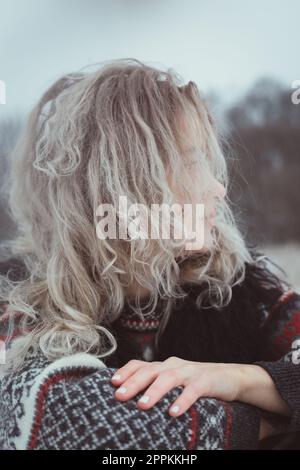 Nahaufnahme einer Frau mit lockigem Haar in einem warmen Pullover im Außenporträt Stockfoto