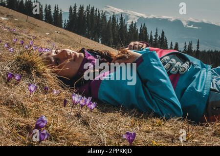 Nahaufnahme weiblicher Wanderer, die zwischen trockenem Gras und Blumen auf einem Porträtbild des Hügels liegt Stockfoto