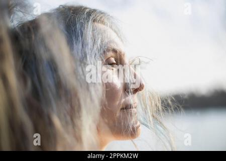 Nahaufnahme Frau mit halb geschlossenen Augen und silbernen Haaren, die auf ein Porträtbild fällt Stockfoto