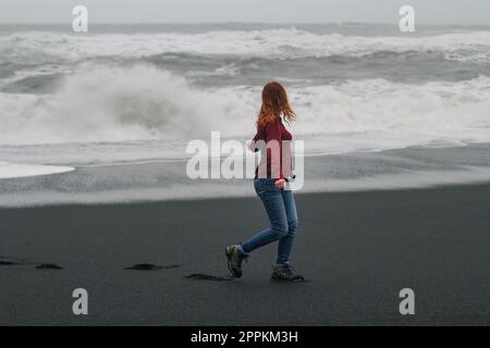 Junge Touristen, die am leeren Strand Islands entlang spazieren gehen und malerische Fotos machen Stockfoto