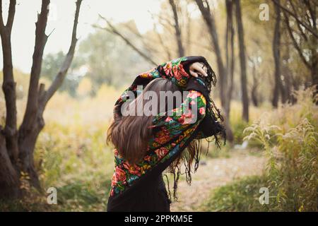 Frau mit geblümtem Schal, die sich vor Sonnenlicht versteckt, malerische Fotografie Stockfoto