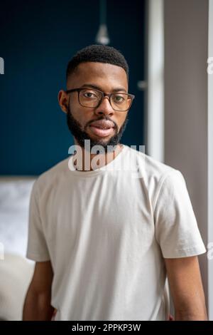 Seriöser junger afroamerikanischer Hausbesitzer, der sich in der Wohnung posiert Stockfoto